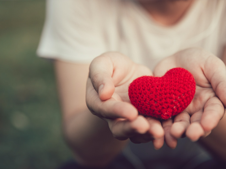 Hands holding a heart symbolizing helping hands