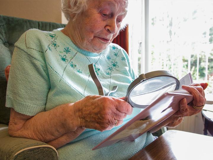 Older woman with low vision using magnifier to read