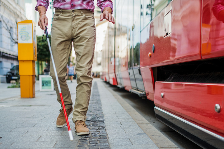 Vision impaired man with white cane preparing to board public transportation