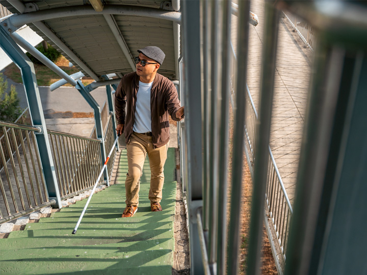 Vision impaired man climbs stairs with white cane<br />
